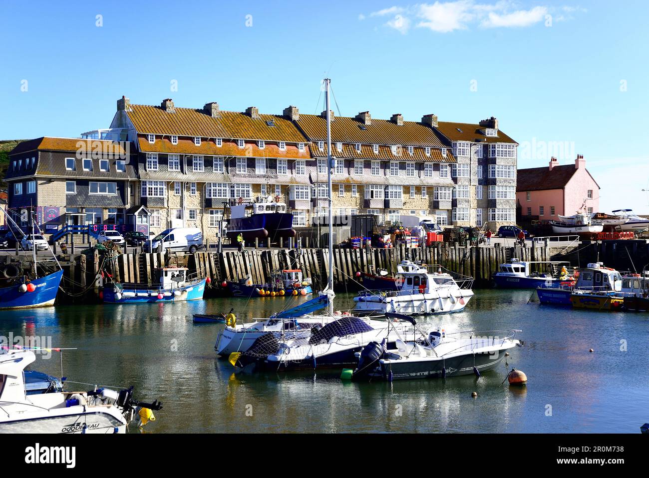 Bateaux de pêche amarrés dans le port avec des appartements à l'arrière, West Bay, Dorset, Royaume-Uni, Europe. Banque D'Images