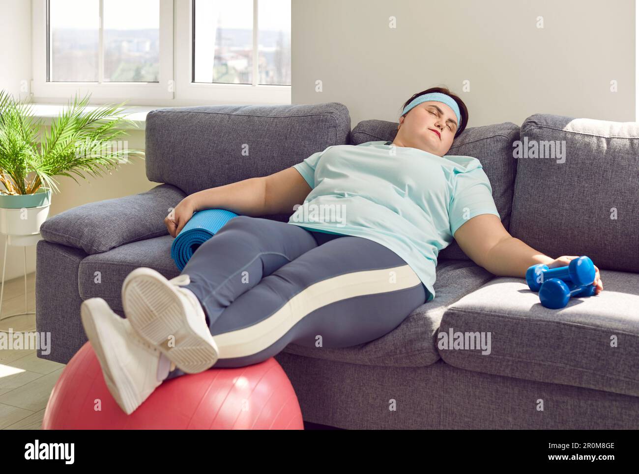 Drôle de femme de graisse s'endormir sur le canapé au lieu d'avoir  l'entraînement de fitness avec l'équipement de sport Photo Stock - Alamy