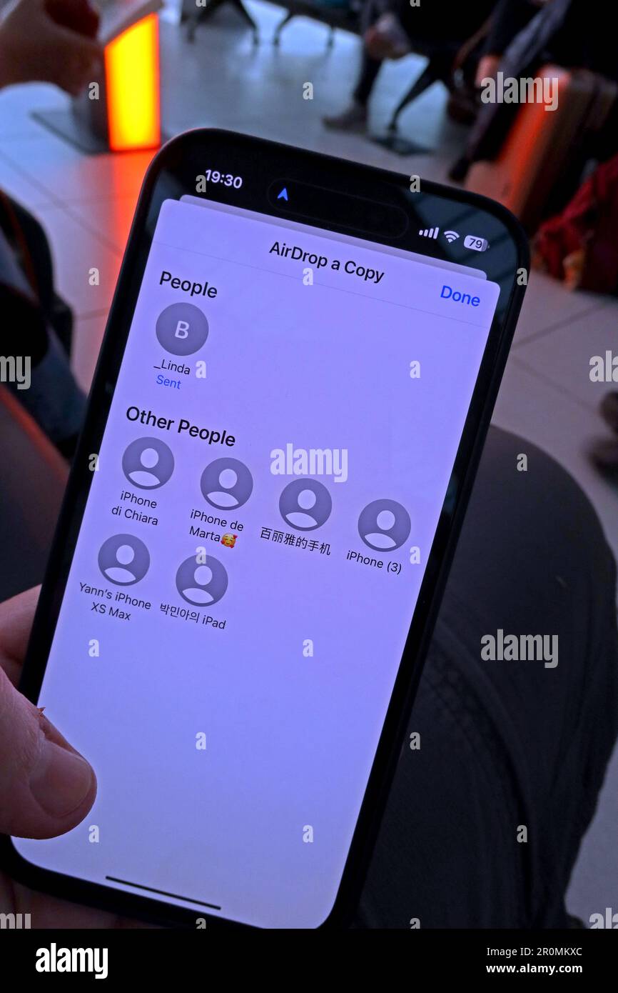 Dangers de partager une image en utilisant le transfert AirDrop dans un lieu public, comme un aéroport, vers des téléphones étrangers proches. Banque D'Images