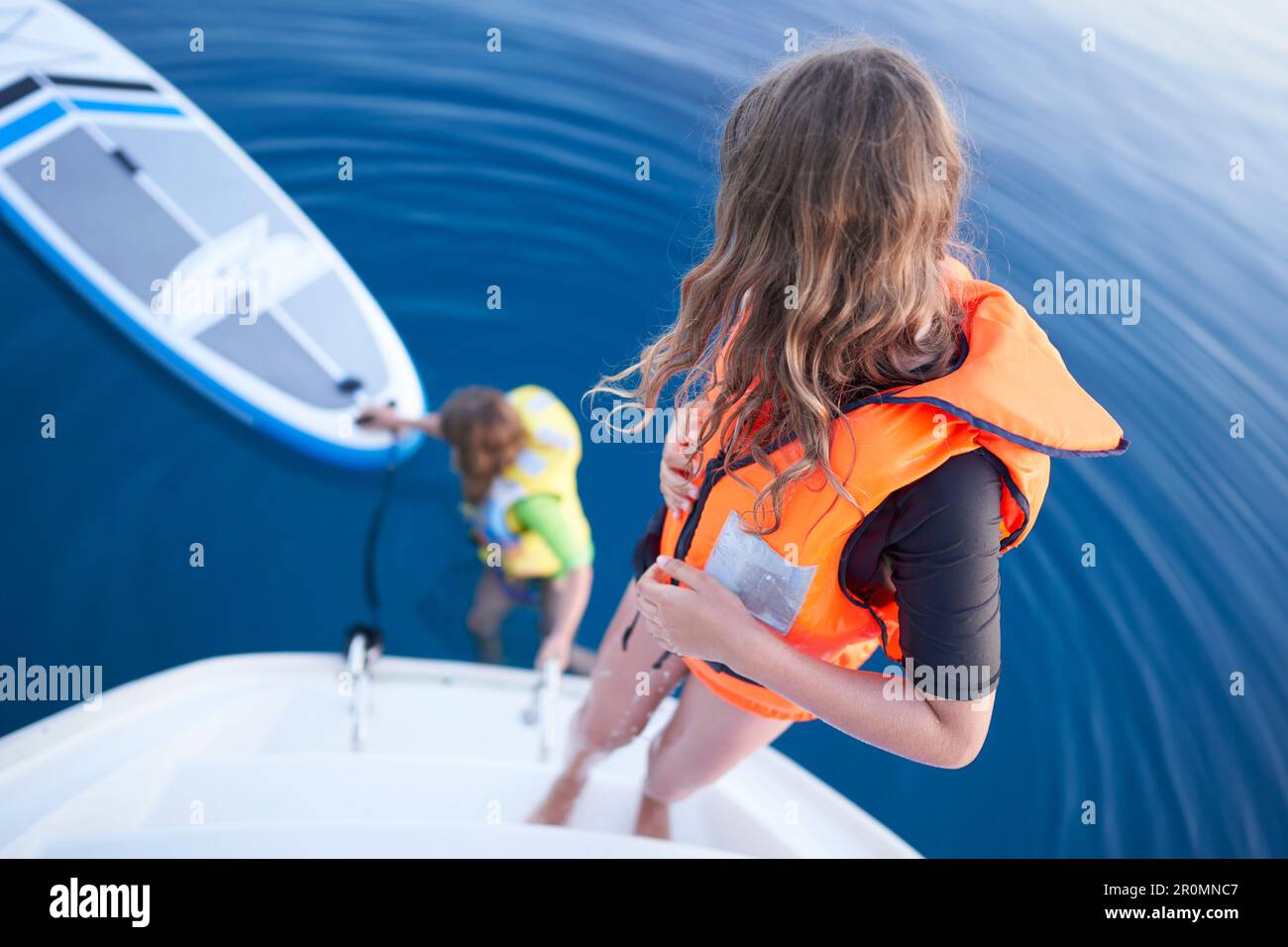 Deux filles avec gilets de sauvetage et SUP Bay de Tomozina, Cres, Croatie Banque D'Images