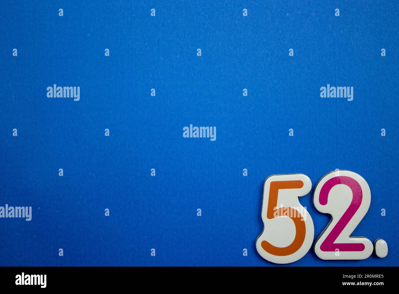 Le numéro 52, placé sur le bord d'un fond bleu, photographié par le dessus, de couleur orange et rouge. Banque D'Images