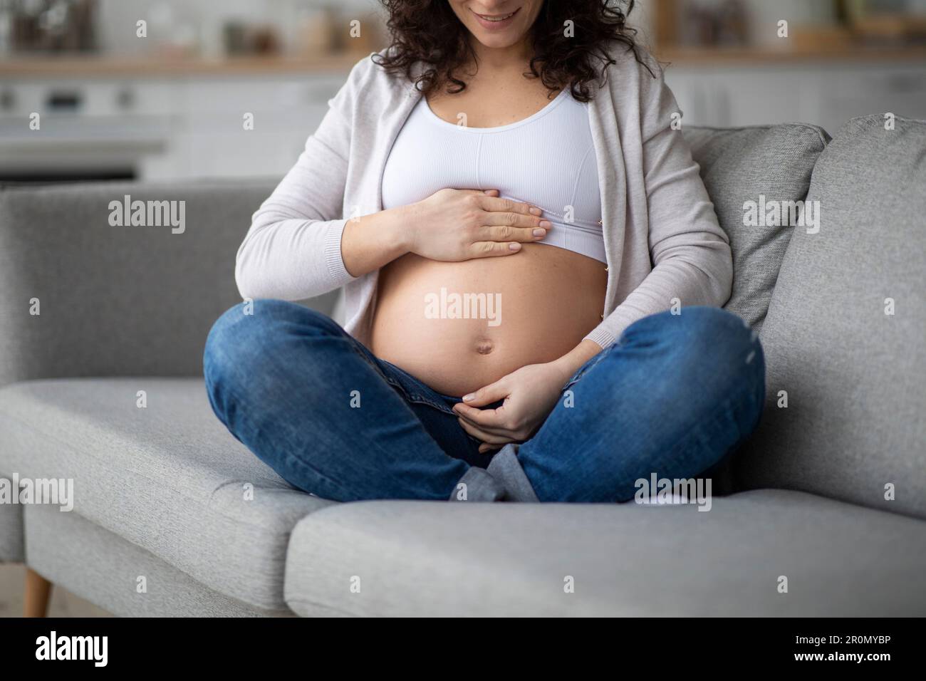 Âge maternel avancé. Femme enceinte souriante embrassant Belly à la maison, croppée Banque D'Images