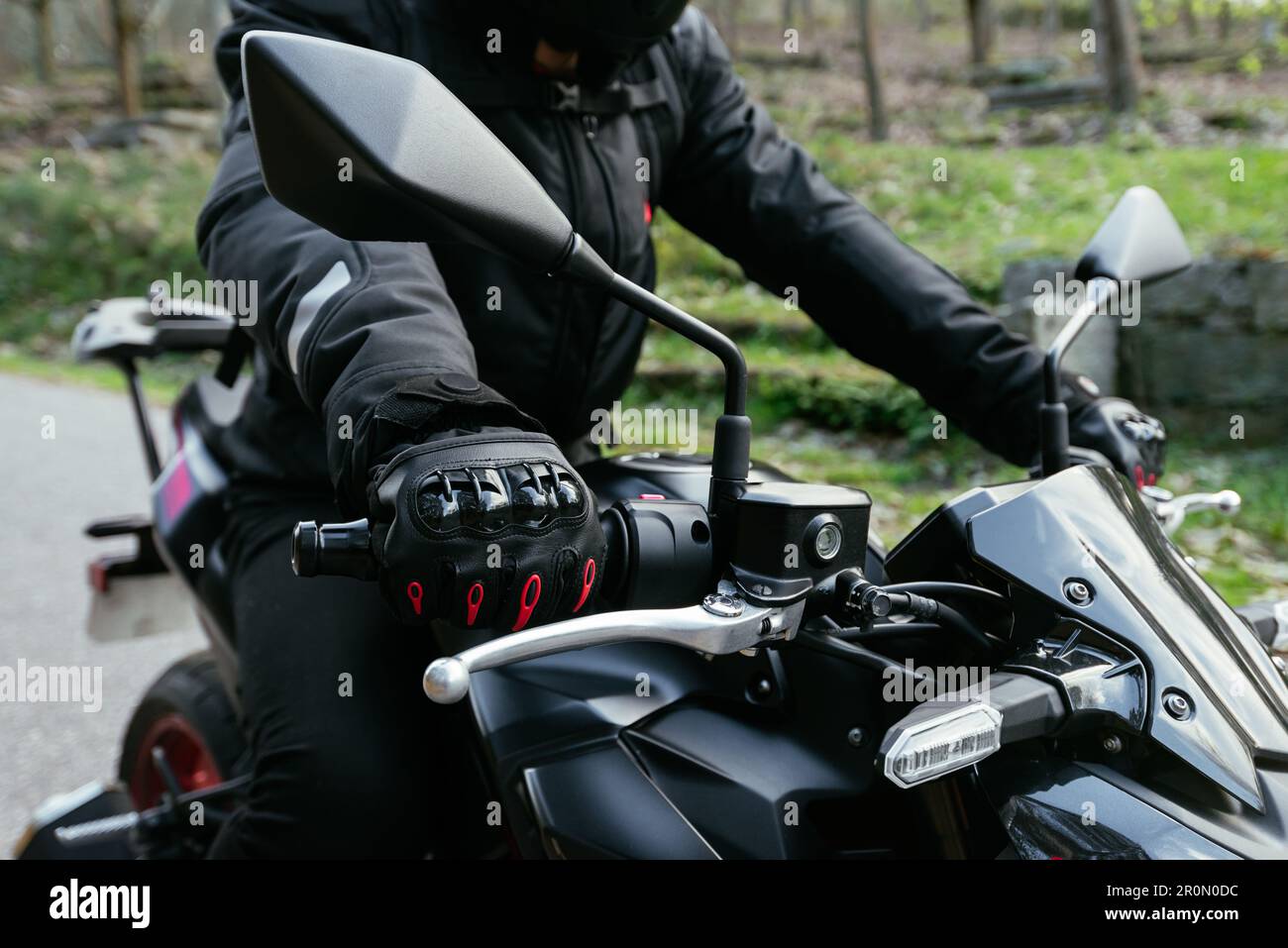 Motard court non reconnaissable dans un casque de protection et une veste  en cuir confortable avec gants de main à bord d'une moto par beau temps en  campagne Photo Stock - Alamy