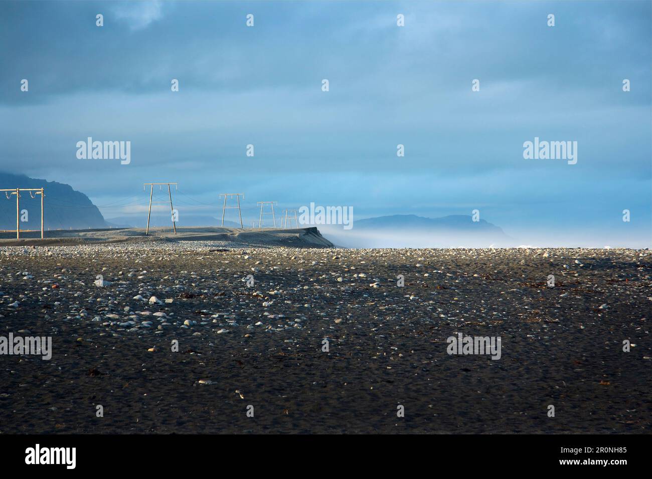 Vue sur les pylônes d'électricité à côté du périphérique, au premier plan une plage de sable volcanique noir dans le sud-est de l'Islande, l'Islande, l'Europe Banque D'Images