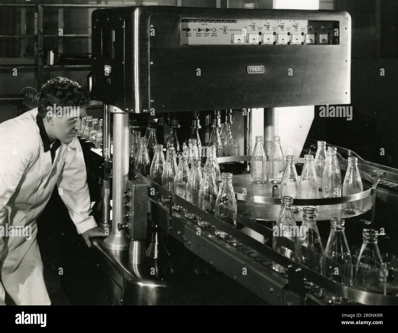 Les bouilloires à lait passent par la machine automatique d'inspection des bouteilles pour détecter les défauts, UK 1966 Banque D'Images