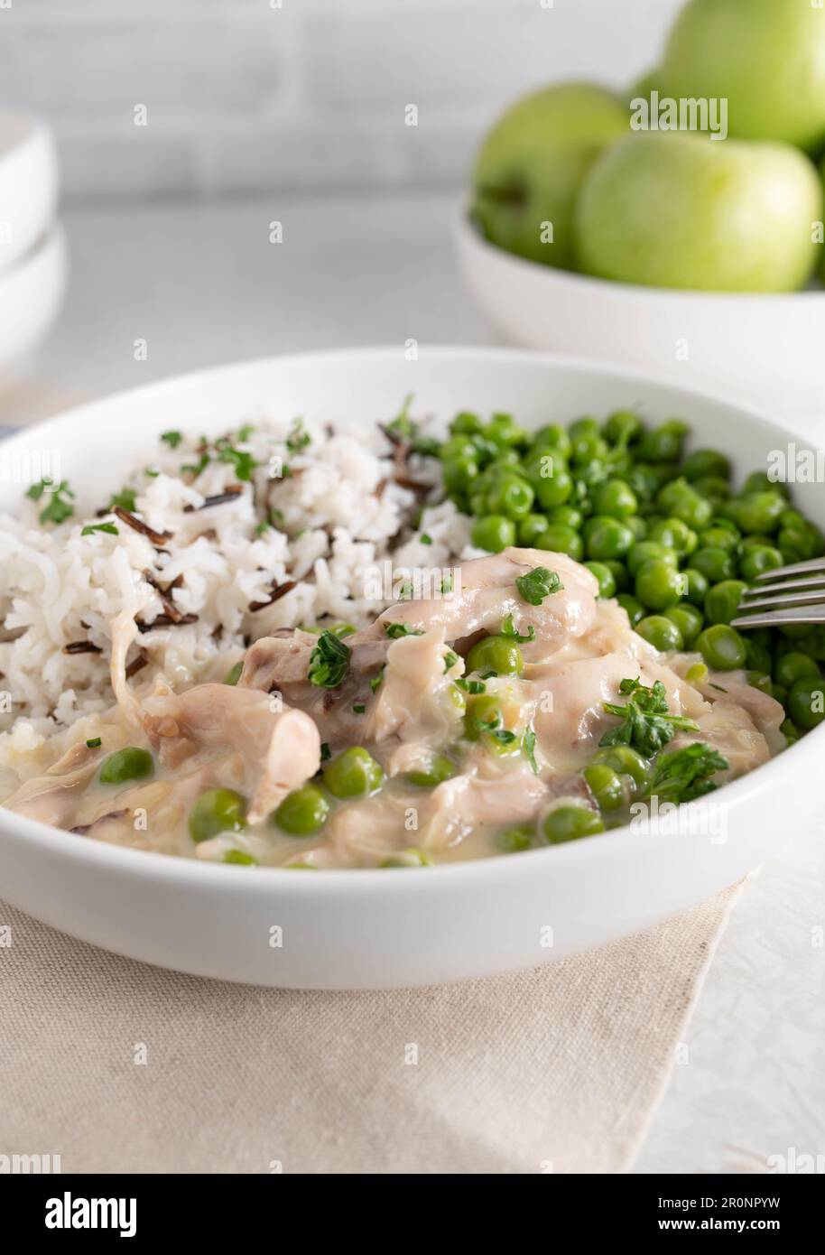 Fricassée de poulet avec basmati, riz sauvage et pois verts beurrés sur une assiette Banque D'Images