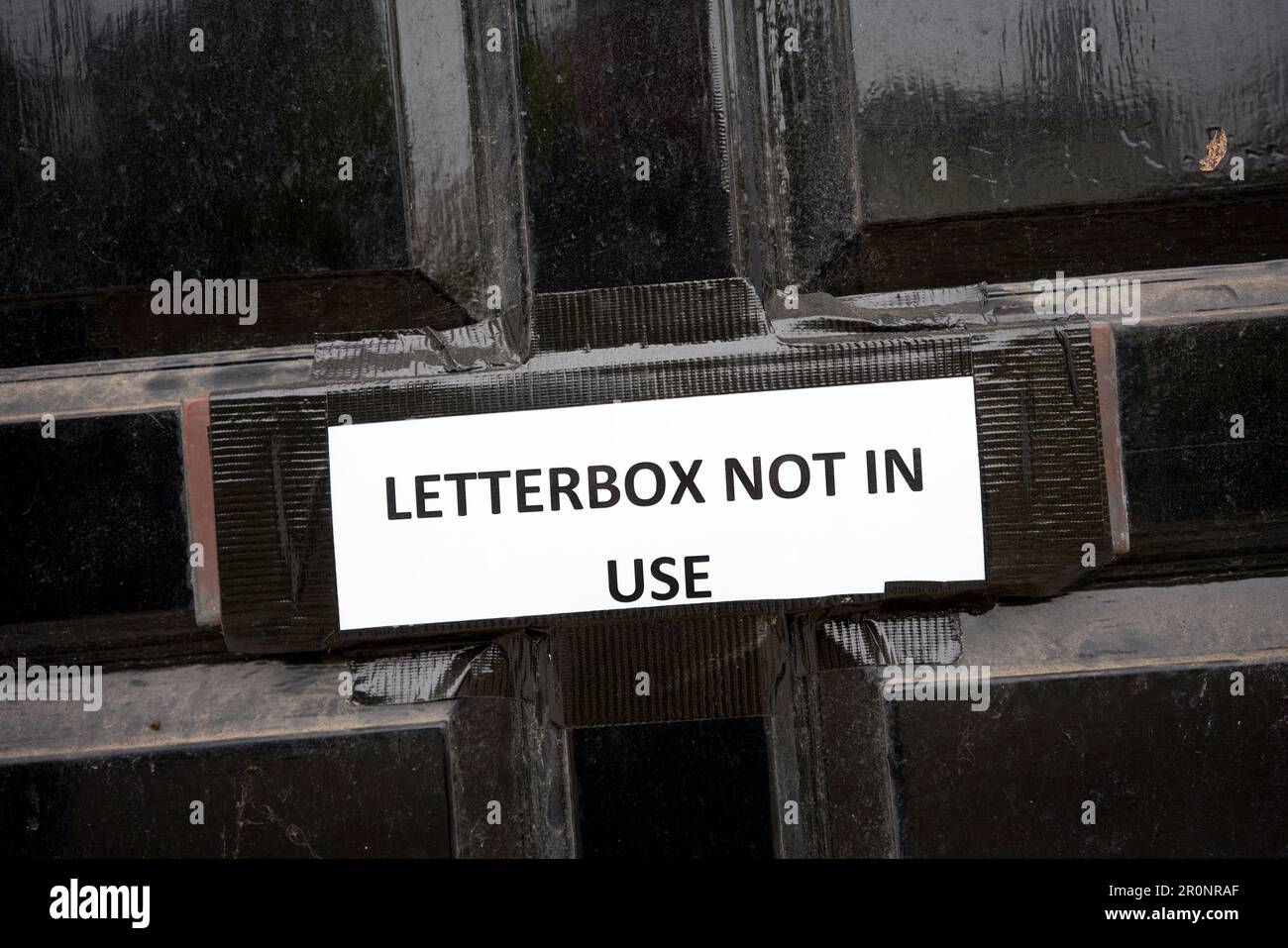 Boîte aux lettres non utilisée affiche collée sur une boîte aux lettres dans une porte noire Banque D'Images
