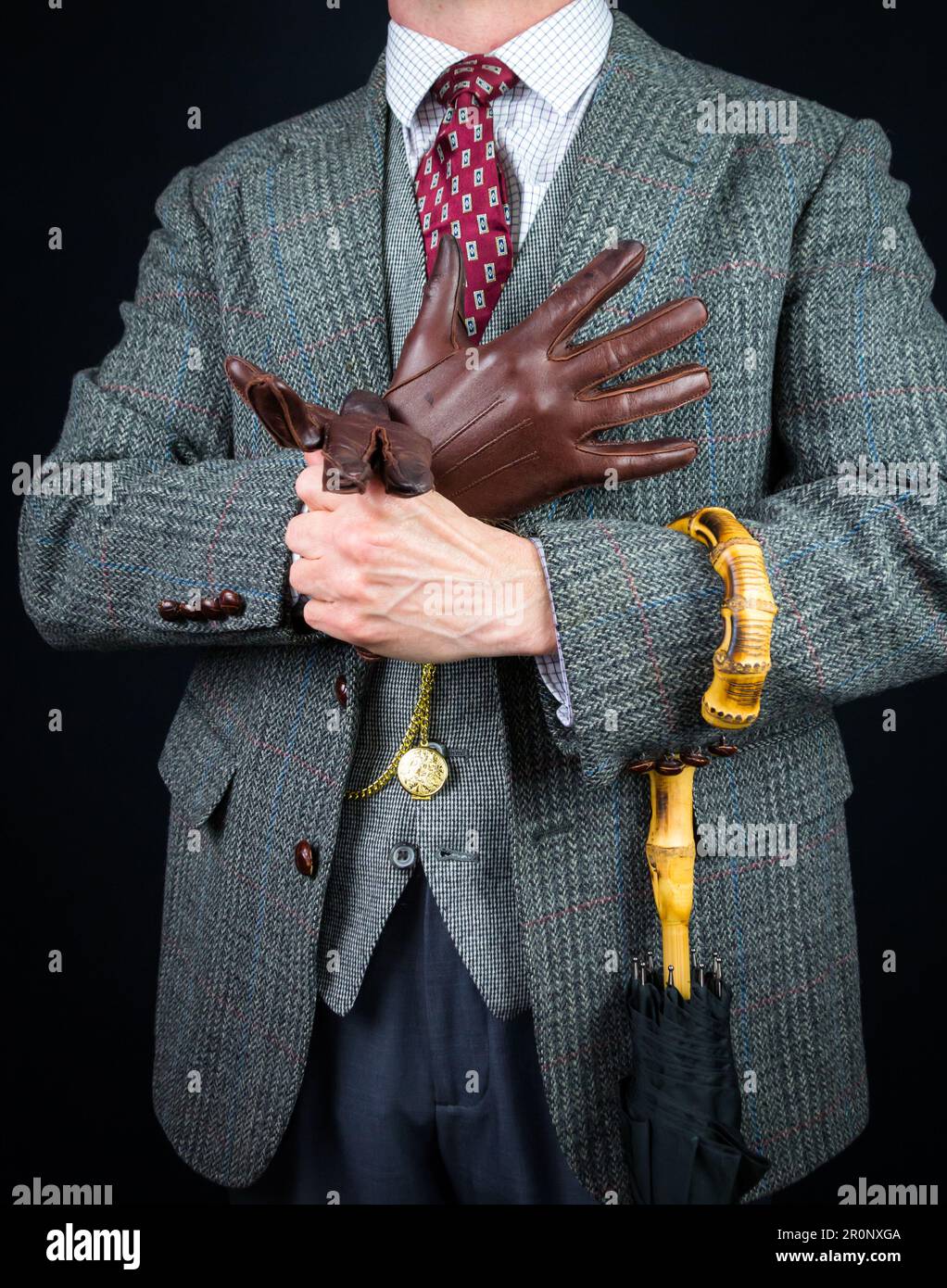 Portrait de l'homme en costume en tweed et parapluie tirant sur les gants en cuir. Style vintage et mode rétro d'un gentleman britannique classique. Banque D'Images