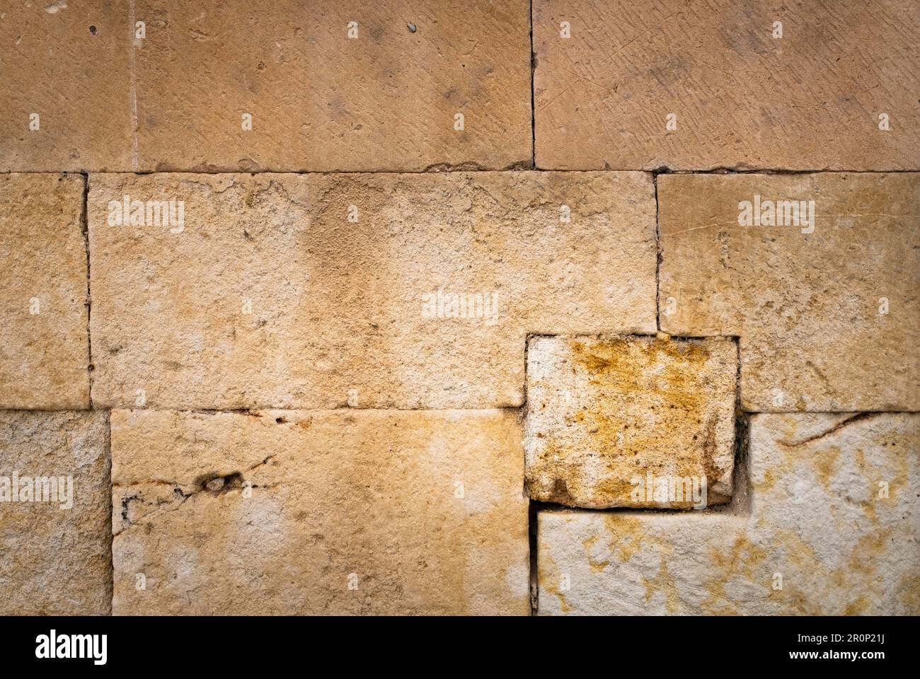 Grand mur en pierre d'un vieux bâtiment, avec beaucoup de texture et de tons chauds, à utiliser comme pochoir ou comme fond. Banque D'Images