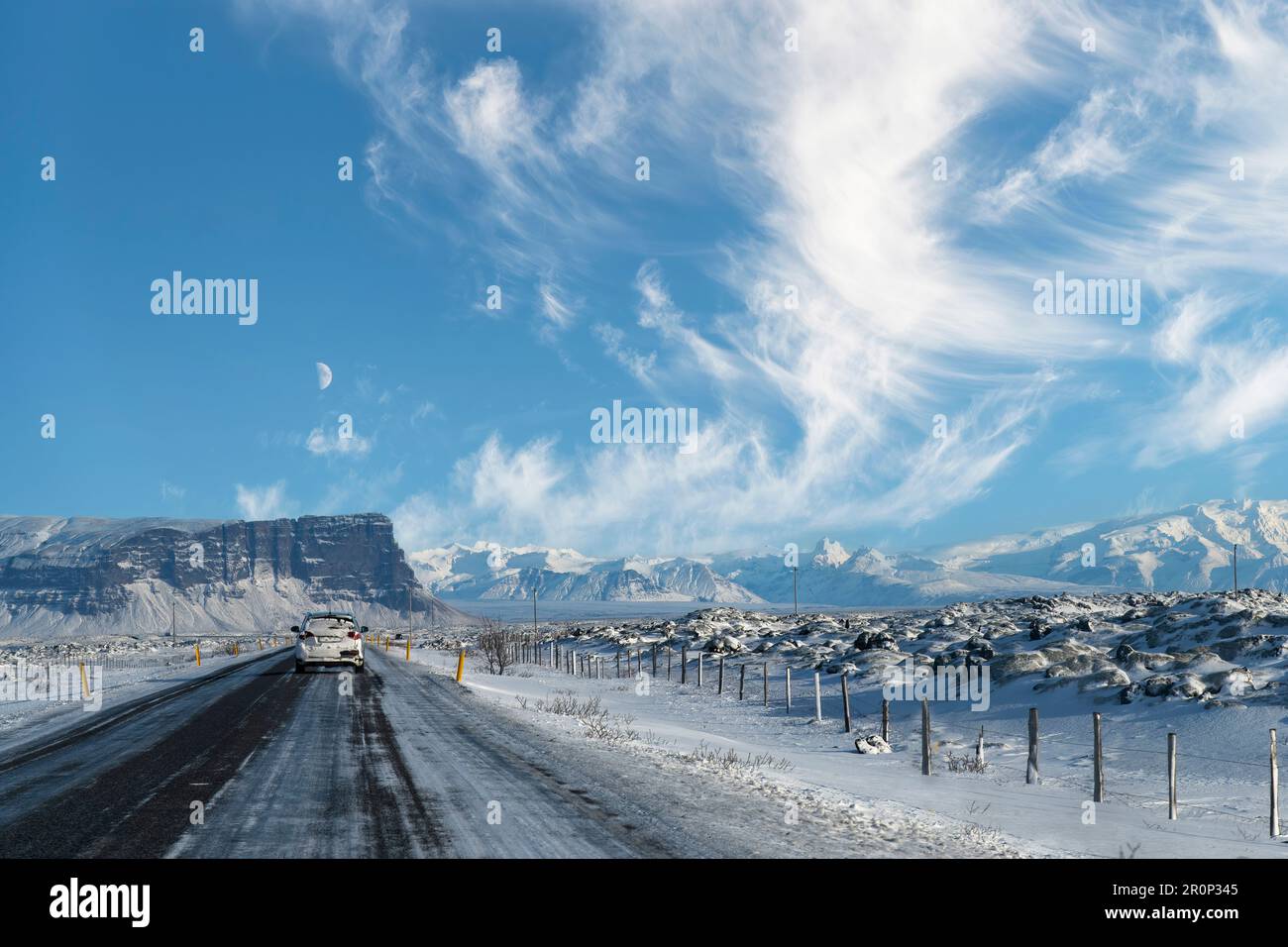 Vue du conducteur sur la route 1 de l'Islande à travers un paysage montagneux enneigé avec vue sur les premières montagnes du parc national de Vatnajokull Banque D'Images