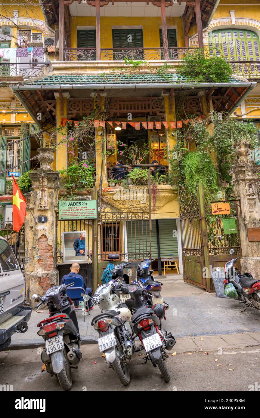 La façade d'une vieille maison de ville avec des vélomoteurs garés en face dans la vieille partie de Hanoi, Vietnam. Banque D'Images