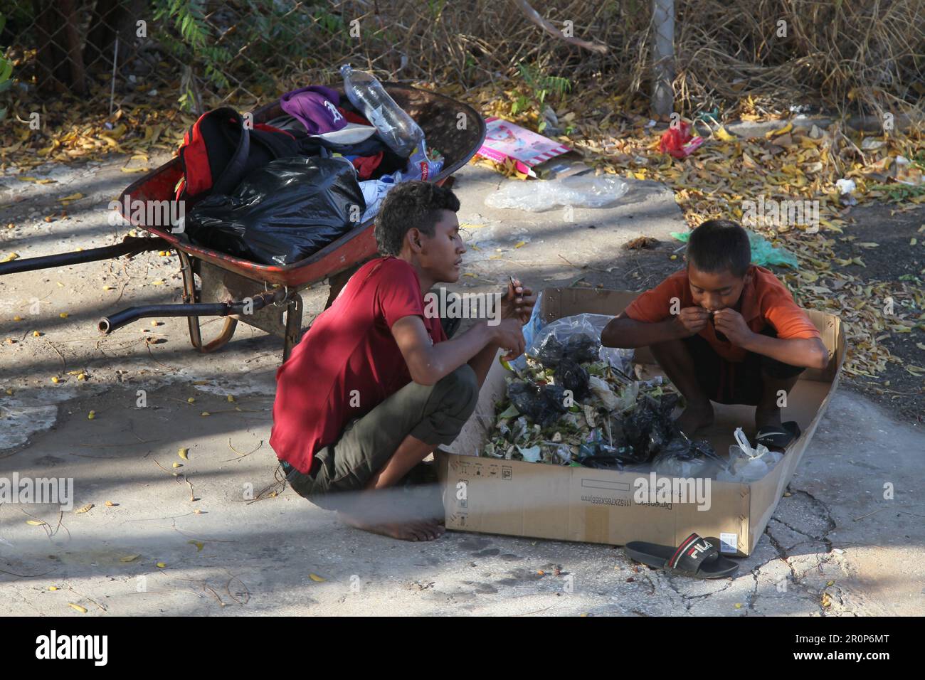 MARACAIBO-VENEZUELA-28-01-2021- les enfants mangent les restes qu'ils reçoivent dans les ordures, tandis qu'ils collectent des matériaux recyclés dans la capitale du pétrole Sta Banque D'Images