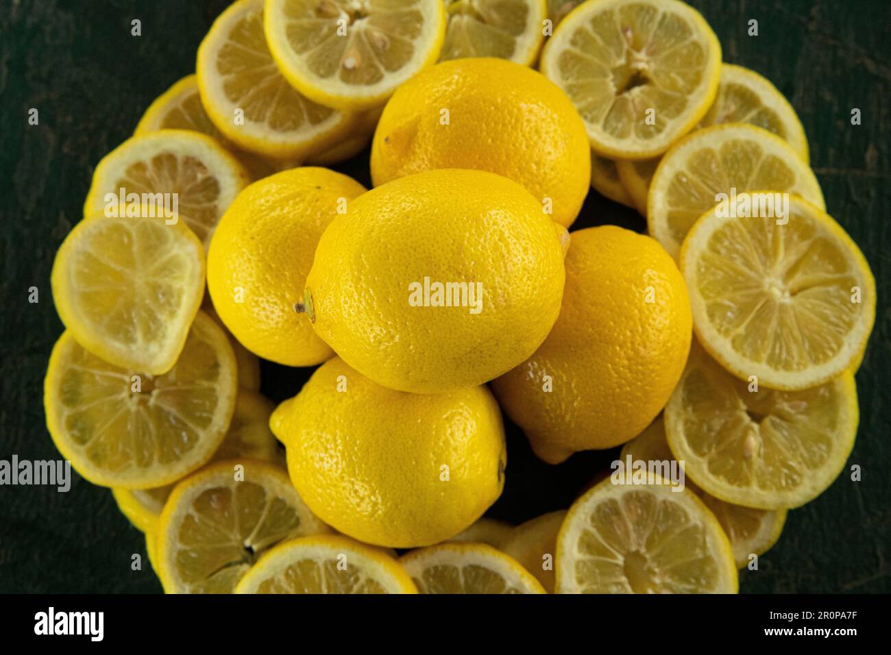 citrons entiers et coupés en tranches disposés de façon circulaire sur une vieille table à éplucher rustique peinte en vert Banque D'Images