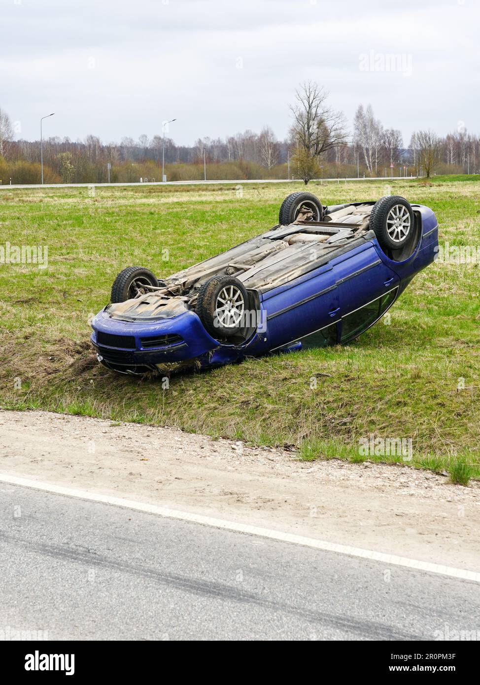 Scène d'accident de voiture, une voiture de tourisme a quitté la route et a renversé avec ses roues vers le haut, véhicule renversé Banque D'Images