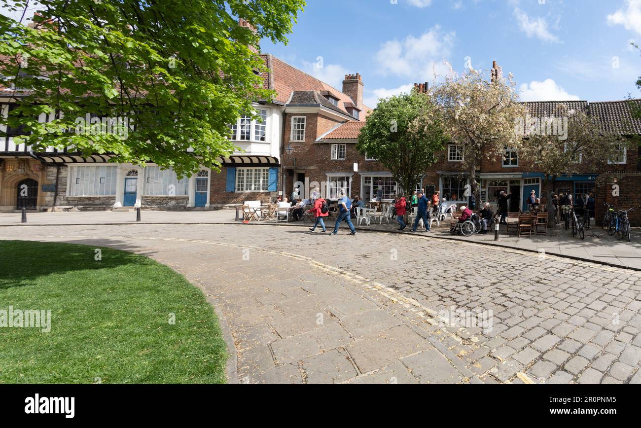 YORK, ROYAUME-UNI - 9 MAI 2023. Les touristes et les habitants apprécient le temps chaud aux tables de cafés en plein air dans la région de York Minster, au Royaume-Uni Banque D'Images