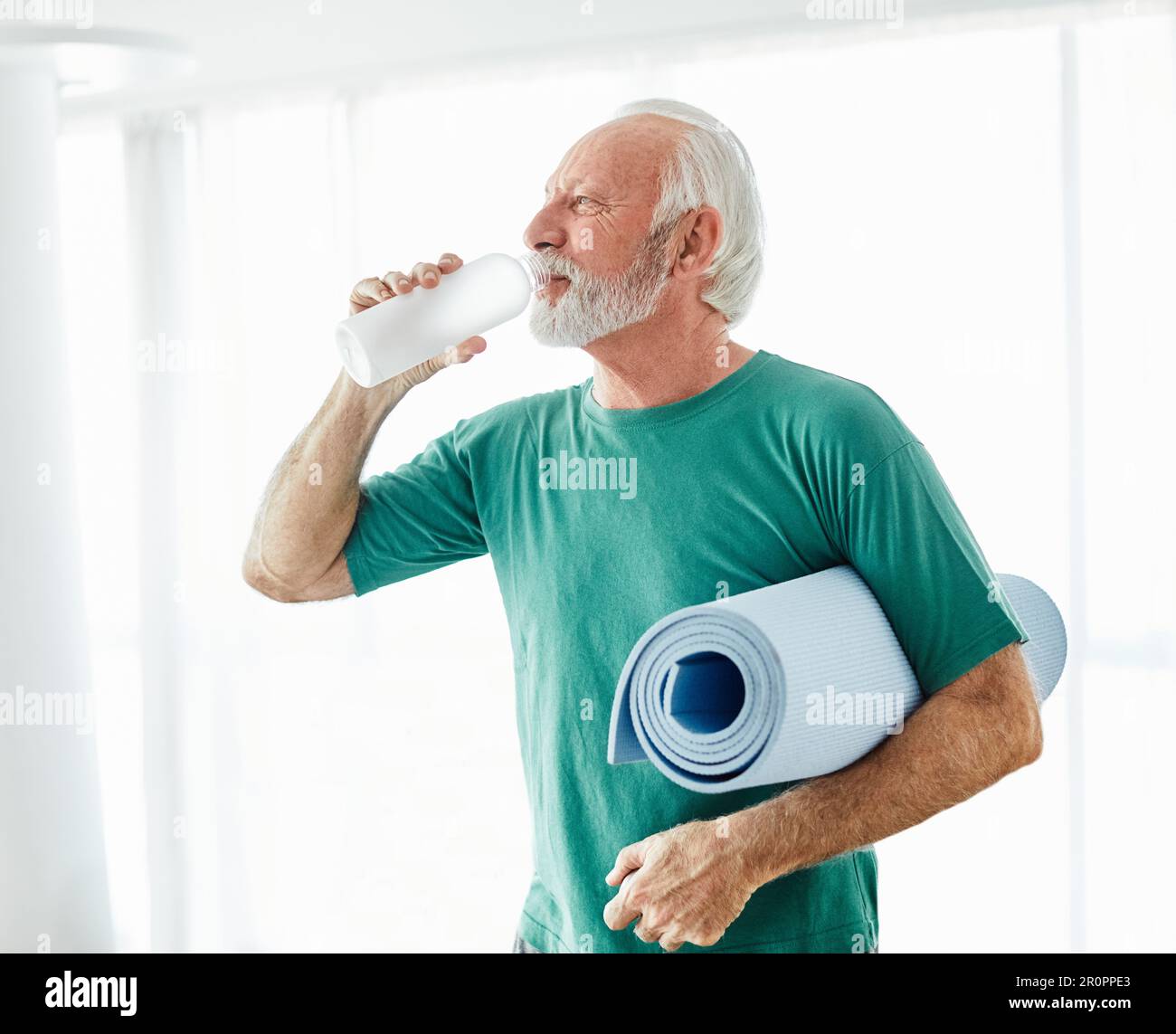 senior exercice actif homme entraînement sport fitness tapis gym fit pilates maison stretching portrait santé posant sourire heureux vieux bouteille d'eau Banque D'Images