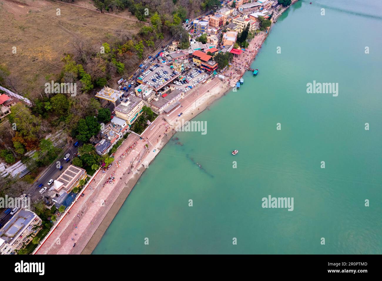 tir de drone aérien d'eau bleue de la rivière ganga s'étendant à distance avec des marches escaliers sur la rive de la rivière avec temple et maisons Banque D'Images