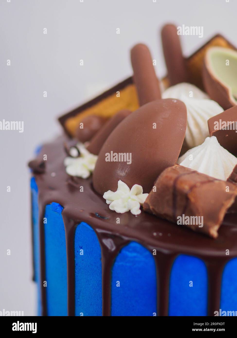 gâteau glacé bleu macro gros plan avec glaçage au chocolat noir et friandises mélangées comme garniture isolée sur fond blanc pour la célébration Banque D'Images