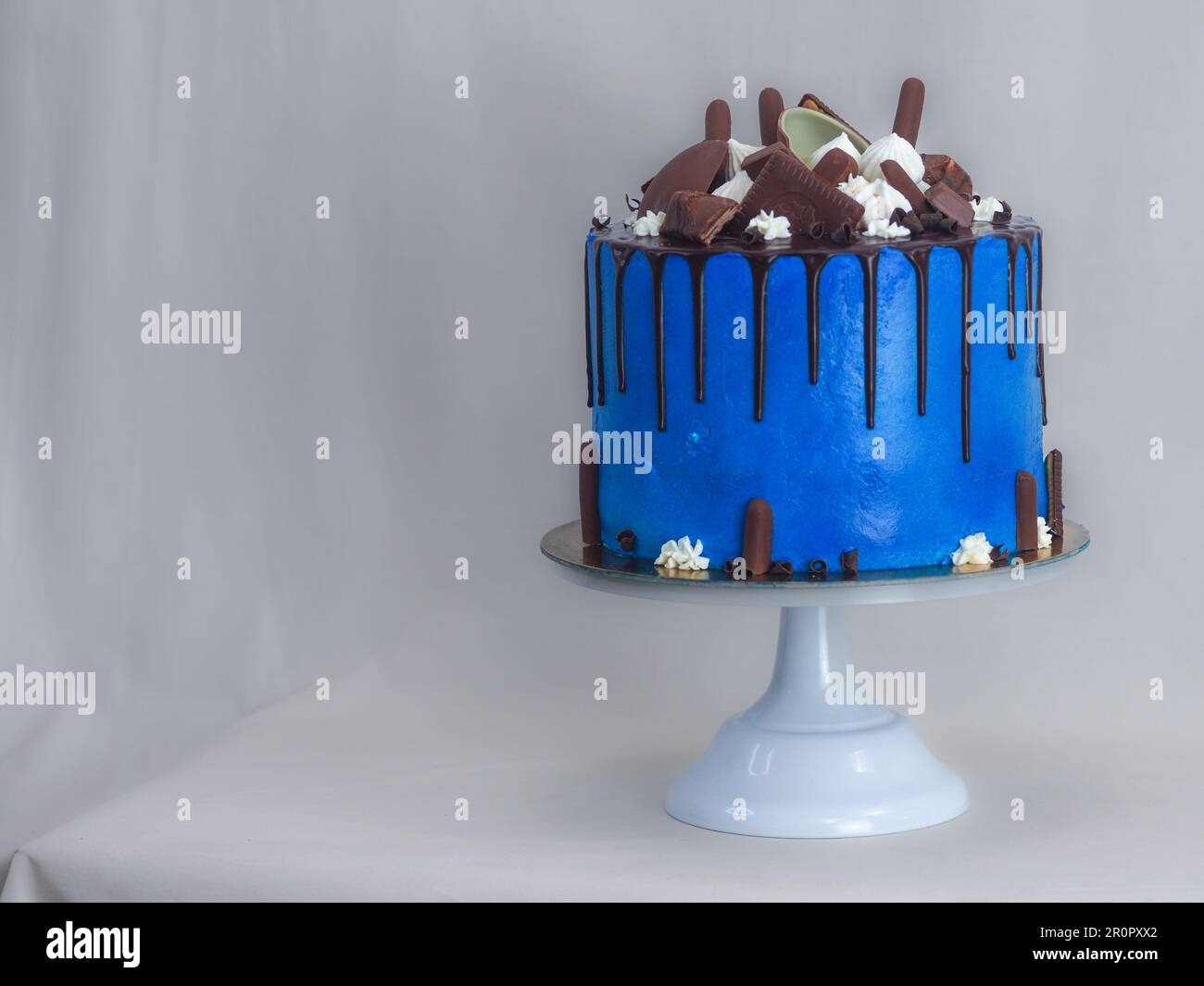 gâteau glacé bleu macro gros plan avec glaçage au chocolat noir et friandises mélangées comme garniture isolée sur fond blanc pour la célébration Banque D'Images