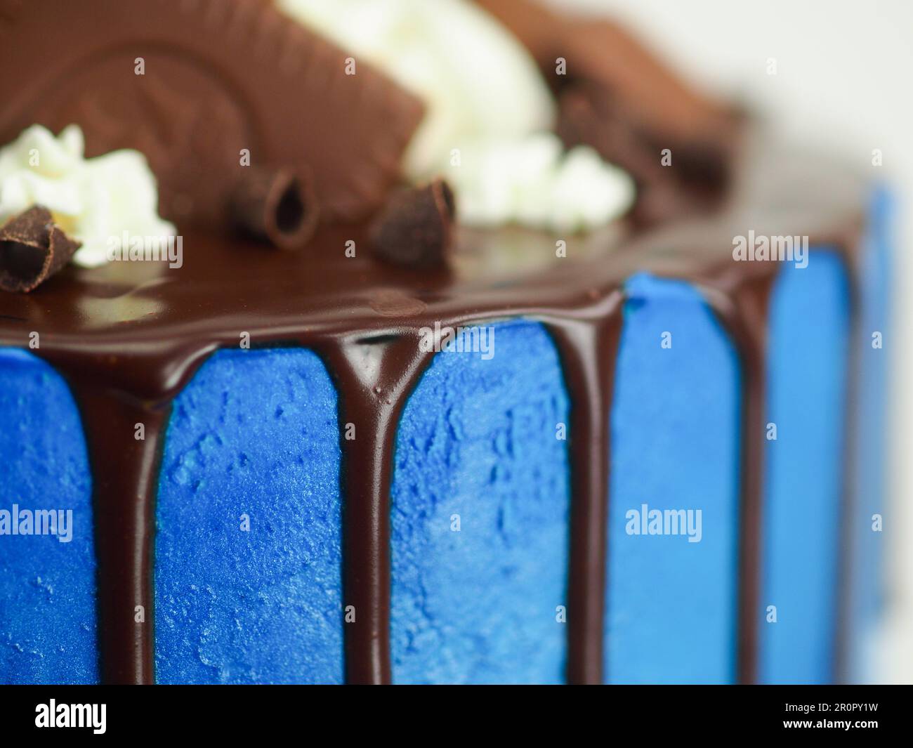 gâteau glacé bleu macro gros plan avec glaçage au chocolat noir et friandises mélangées comme garniture isolée sur fond blanc pour la célébration Banque D'Images