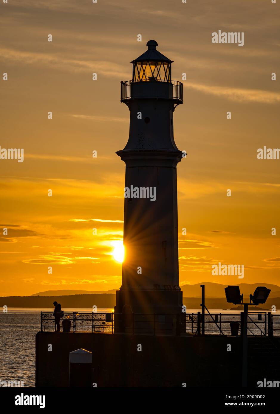 Édimbourg, Écosse, Royaume-Uni, 9th mai 2023. Météo au Royaume-Uni : coucher de soleil au port de Newhaven. Un coucher de soleil coloré au-dessus du phare silhoueté sur le Firth of Forth. Crédit : Sally Anderson/Alay Live News Banque D'Images