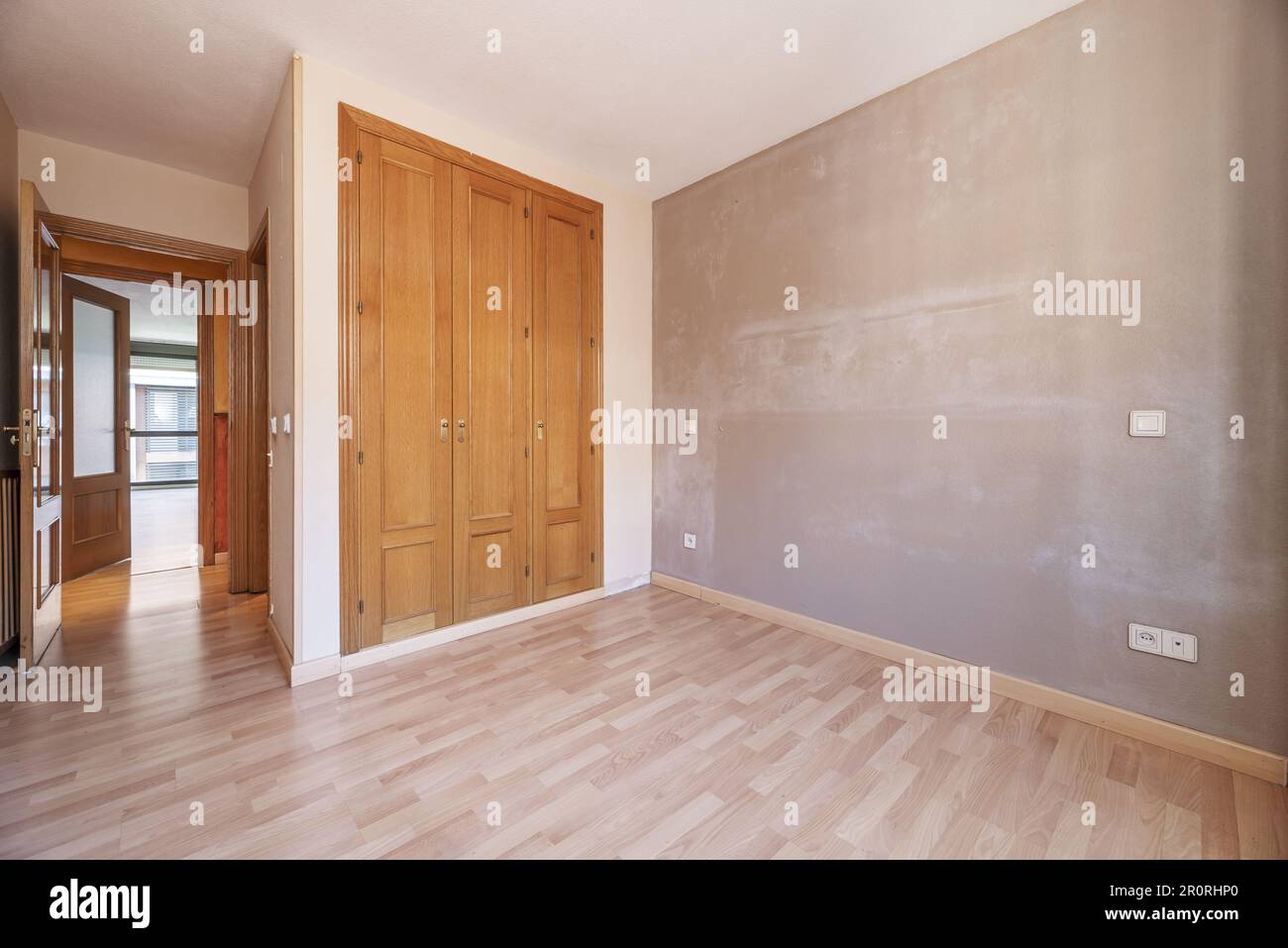 Chambre vide avec les murs ayant besoin d'une nouvelle couche de peinture et avec une armoire intégrée avec des portes en bois Banque D'Images