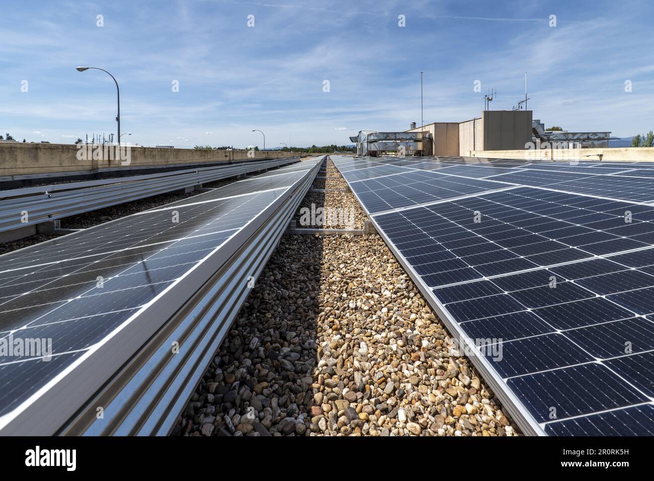 Panneaux solaires modernes installés sur le toit d'un bâtiment avec du gravier sur une journée de charge claire Banque D'Images
