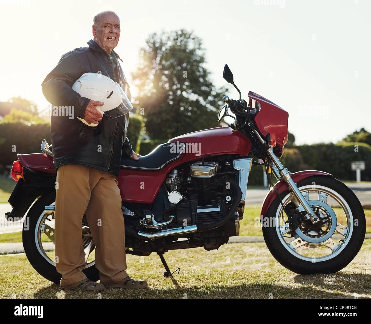 Juste parce que je suis vieux, ça ne veut pas dire que je ne peux pas m'amuser. un homme âgé debout à l'extérieur près de sa moto. Banque D'Images