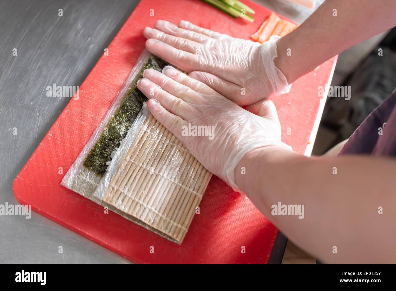 Faire cuire des sushis roulés avec du saumon, du fromage et du concombre. Photo de haute qualité Banque D'Images