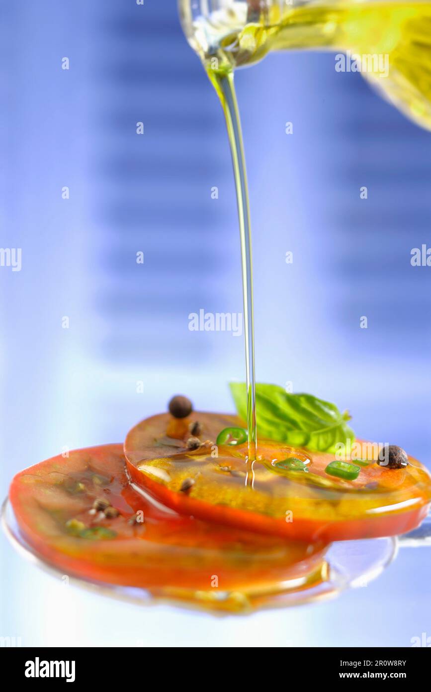 Verser l'huile d'olive sur les tomates tranchées Banque D'Images