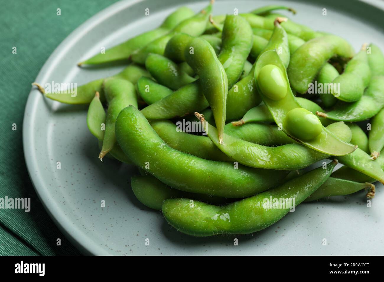 Assiette de haricots verts edamame dans les gousses sur la table, gros plan Banque D'Images
