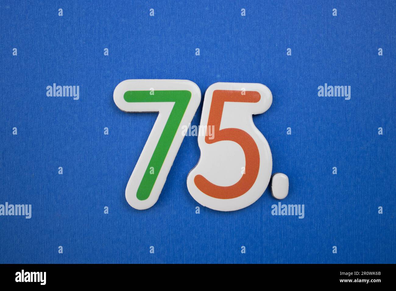 Le numéro 75, placé sur un fond bleu, photographié par le dessus, de couleur verte et rouge. Banque D'Images