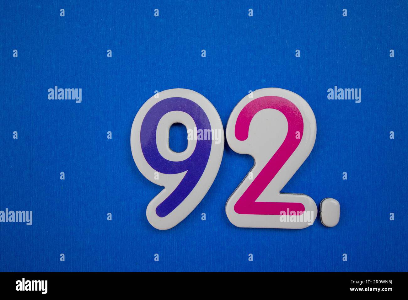 Le numéro 92, placé sur un fond bleu, photographié d'en haut, de couleur bleue et rose. Banque D'Images