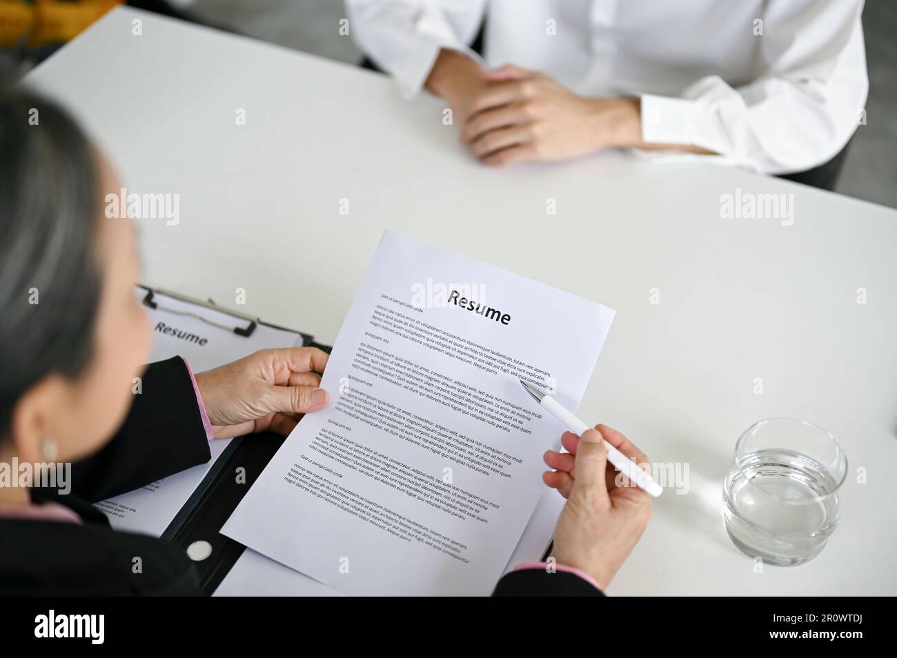 Vue rapprochée d'une femme d'affaires professionnelle senior lisant le curriculum vitae d'un candidat et posant une question pendant une entrevue d'emploi. Banque D'Images