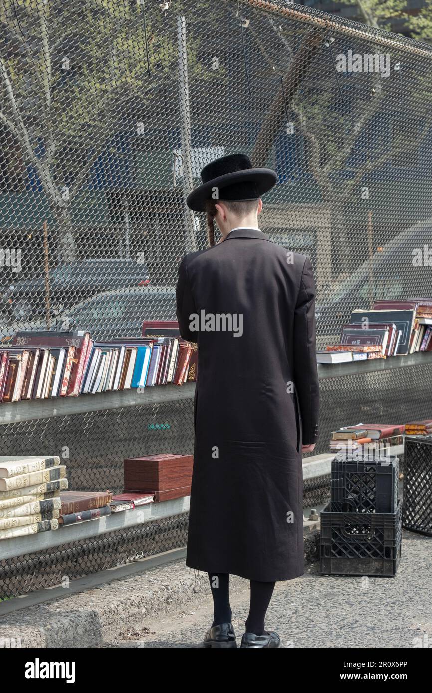 Un jeune juif anonyme portant tout le noir, y compris les boutiques de bas noir pour les livres à une vente pop up extérieure. À Brooklyn, New York. Banque D'Images