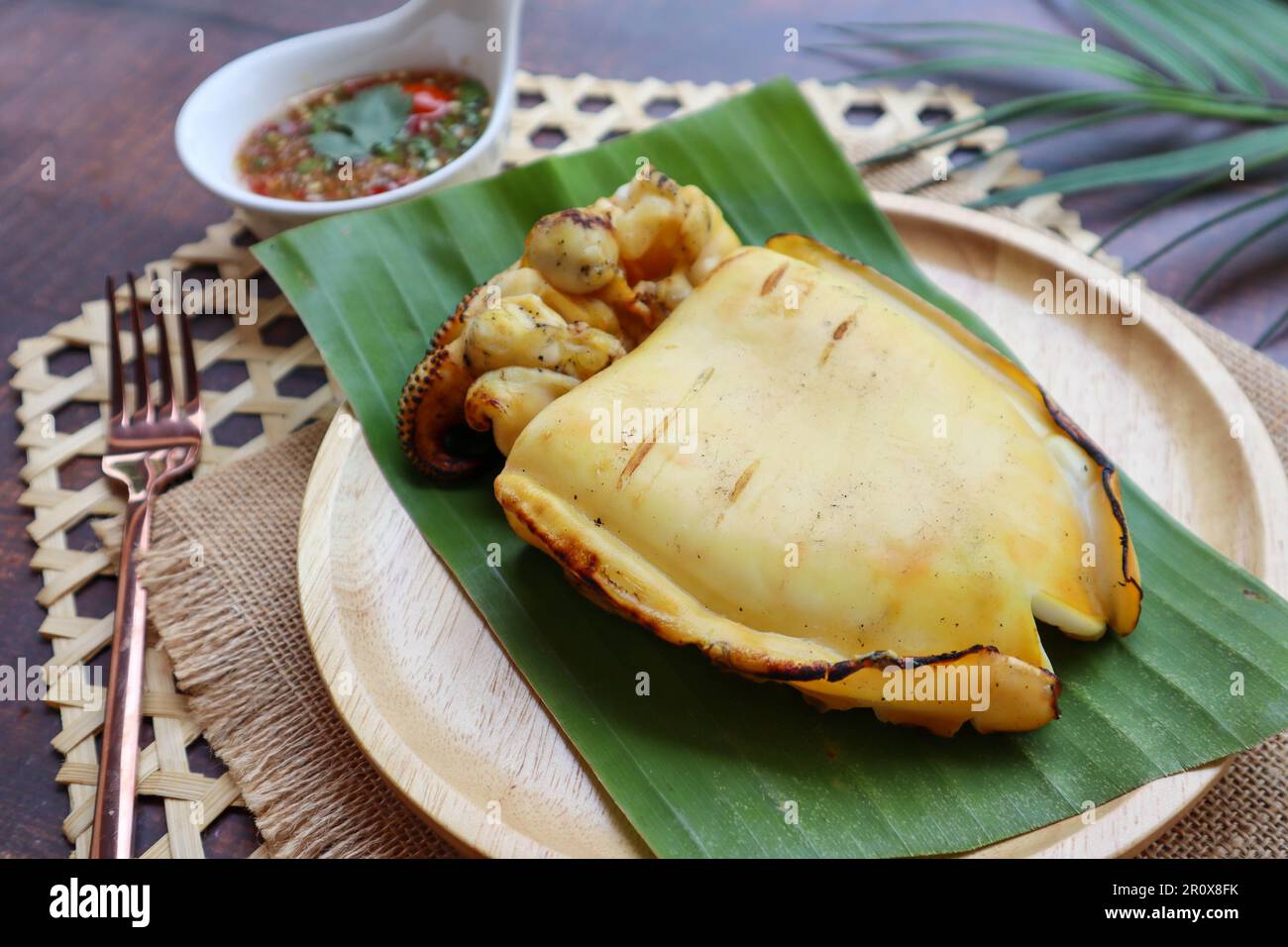 Calamar grillé au charbon de bois servi avec une sauce piquante aux
