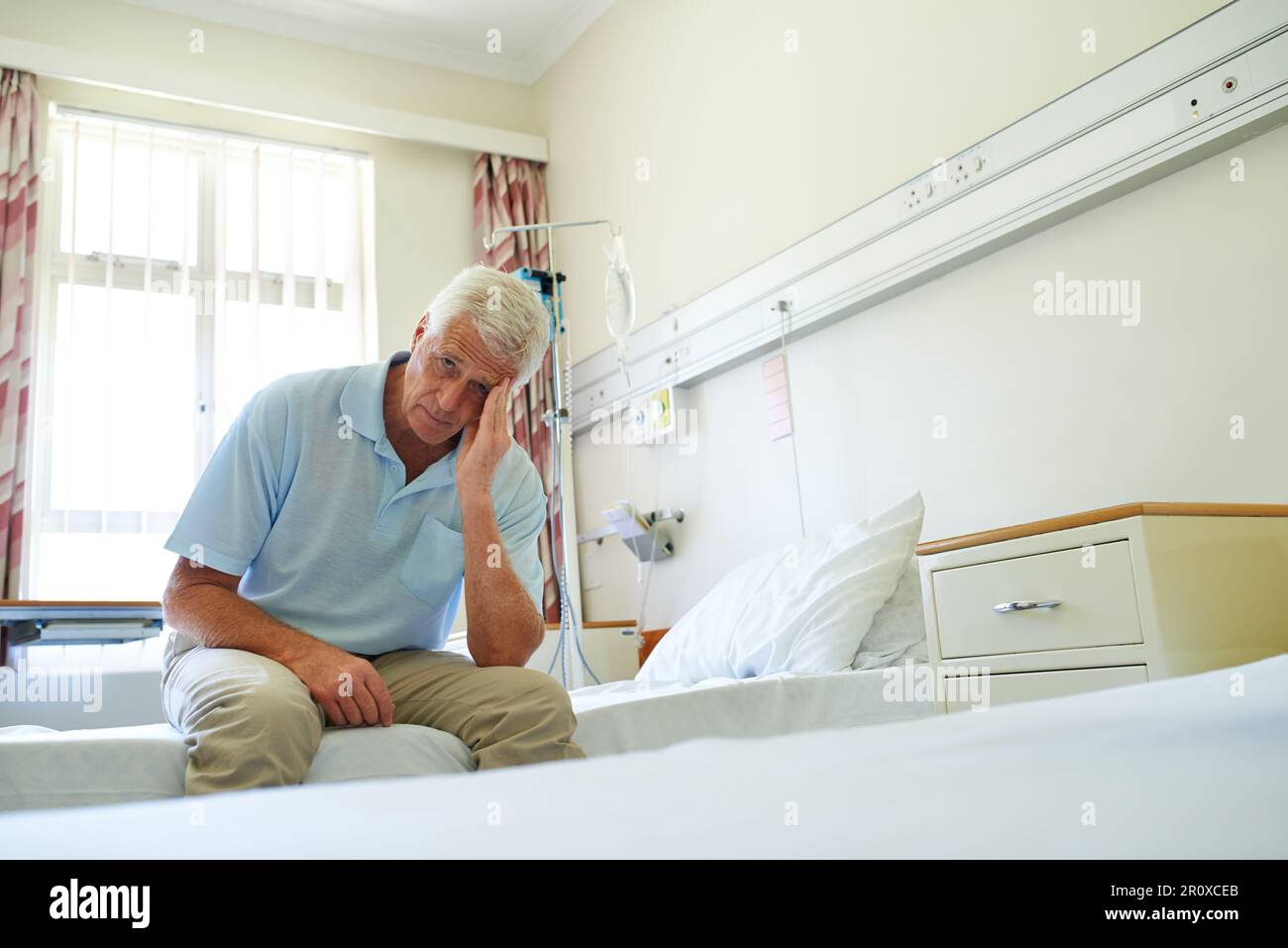 La suite. Portrait d'un homme âgé en douleur assis seul sur un lit dans