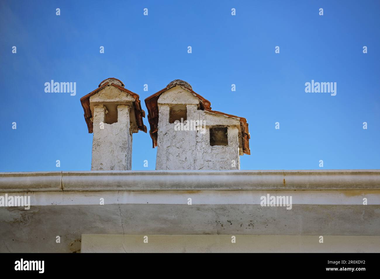 Cheminées à plâtrés lumineux avec toits en tuiles sur un bâtiment en Grèce, ressemblant à de petites maisons, ciel bleu avec espace de copie, focus sélectionné Banque D'Images