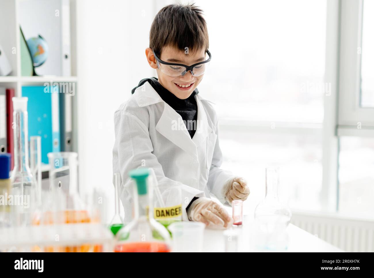 Garçon d'école portant des lunettes de protection faisant une expérience de chimie en classe de sciences élémentaires.Pupille avec tubes d'équipement en laboratoire Banque D'Images
