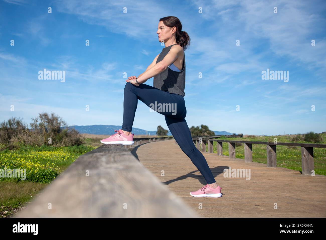 la coureuse fait des exercices d'échauffement à la jambe à l'extérieur Banque D'Images