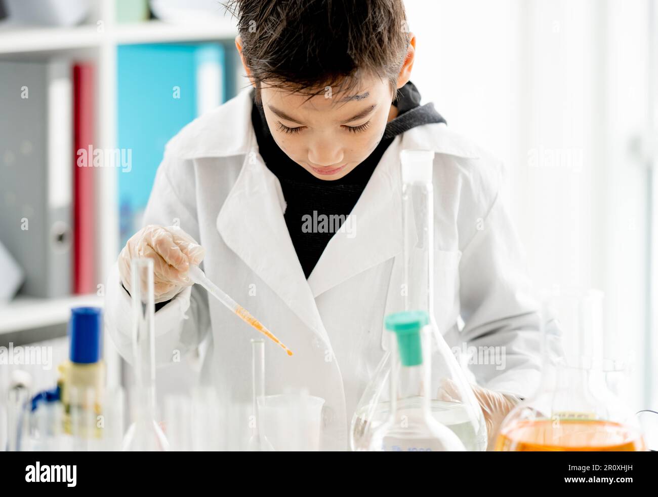 Garçon d'école faisant l'expérience de chimie mesurer des liquides chimiques dans la classe de sciences élémentaires. Pupille intelligente analysant les résultats des tests en laboratoire Banque D'Images