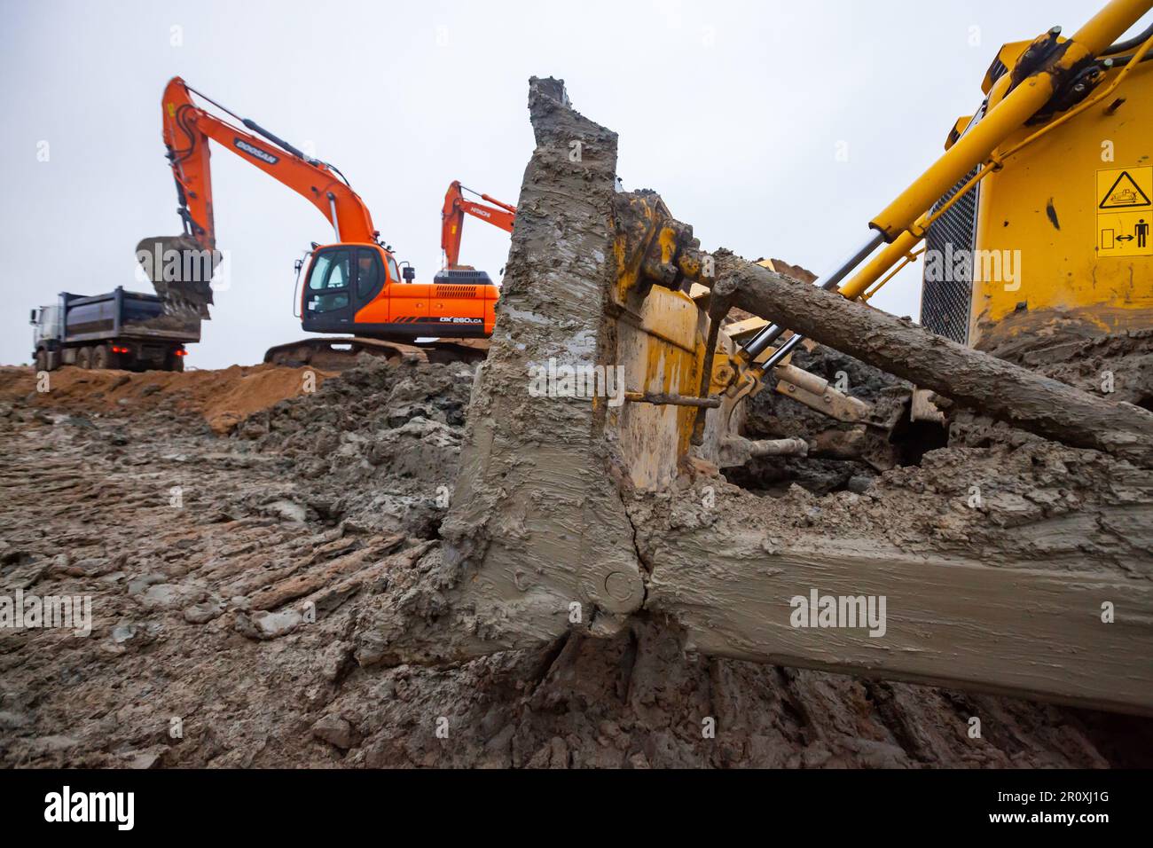 UST-Luga, oblast de Leningrad, Russie - 16 novembre 2021 : excavateurs Doosan et Hitachi sur le chantier. Lame de bouteur sale au premier plan. Banque D'Images