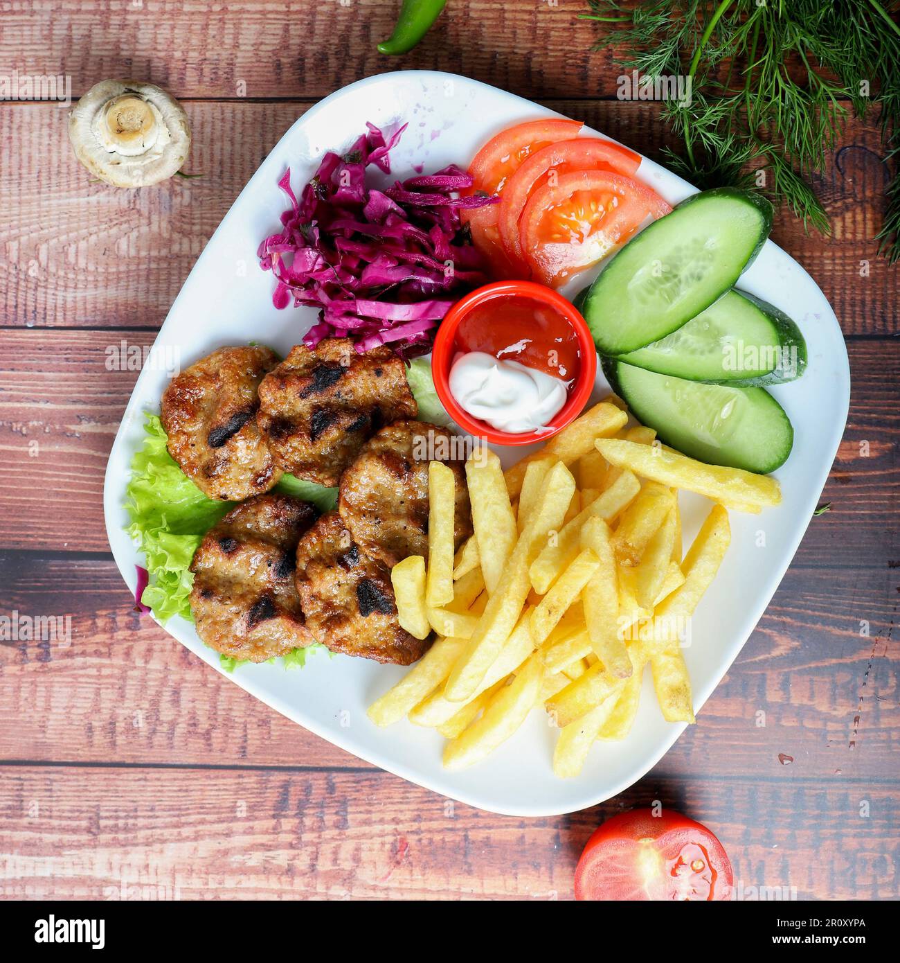 Un délicieux repas avec un steak juteux, des frites croustillantes et une variété de légumes colorés disposés sur une assiette placée sur une table en bois Banque D'Images