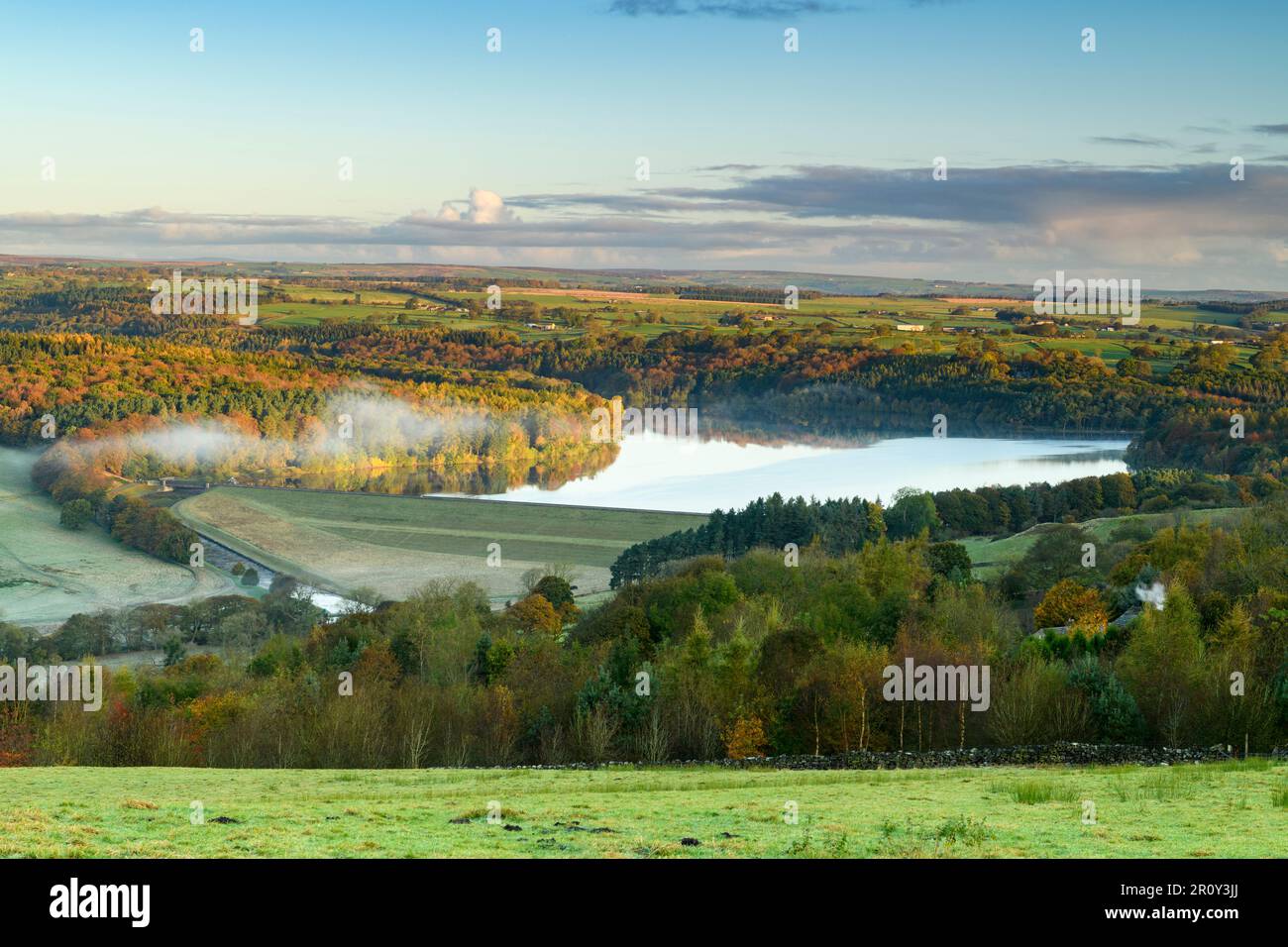 Swinsty Reservoir Sunlight (longue distance, collines colorées, temps brumeux froid ensoleillé, ciel bleu, eau) - Washburn Valley, Yorkshire, Angleterre, Royaume-Uni. Banque D'Images