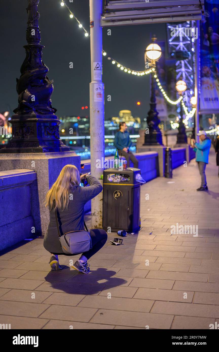 LONDRES - 21 avril 2023 : la photographe féminine capture des scènes urbaines grisantes de la poubelle débordante, de la promenade de la reine et du London Eye hors foyer sous un angle bas Banque D'Images