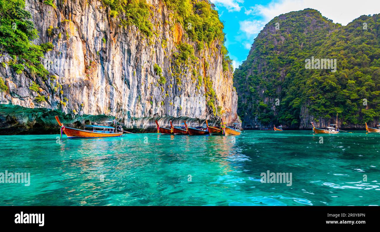 Vue sur les bateaux à longue queue sur l'eau turquoise à l'océan près des îles de Ko Phi Phi, Thaïlande. Concept de vacances exotiques dans le paradis tropical. Roche calcaire Banque D'Images