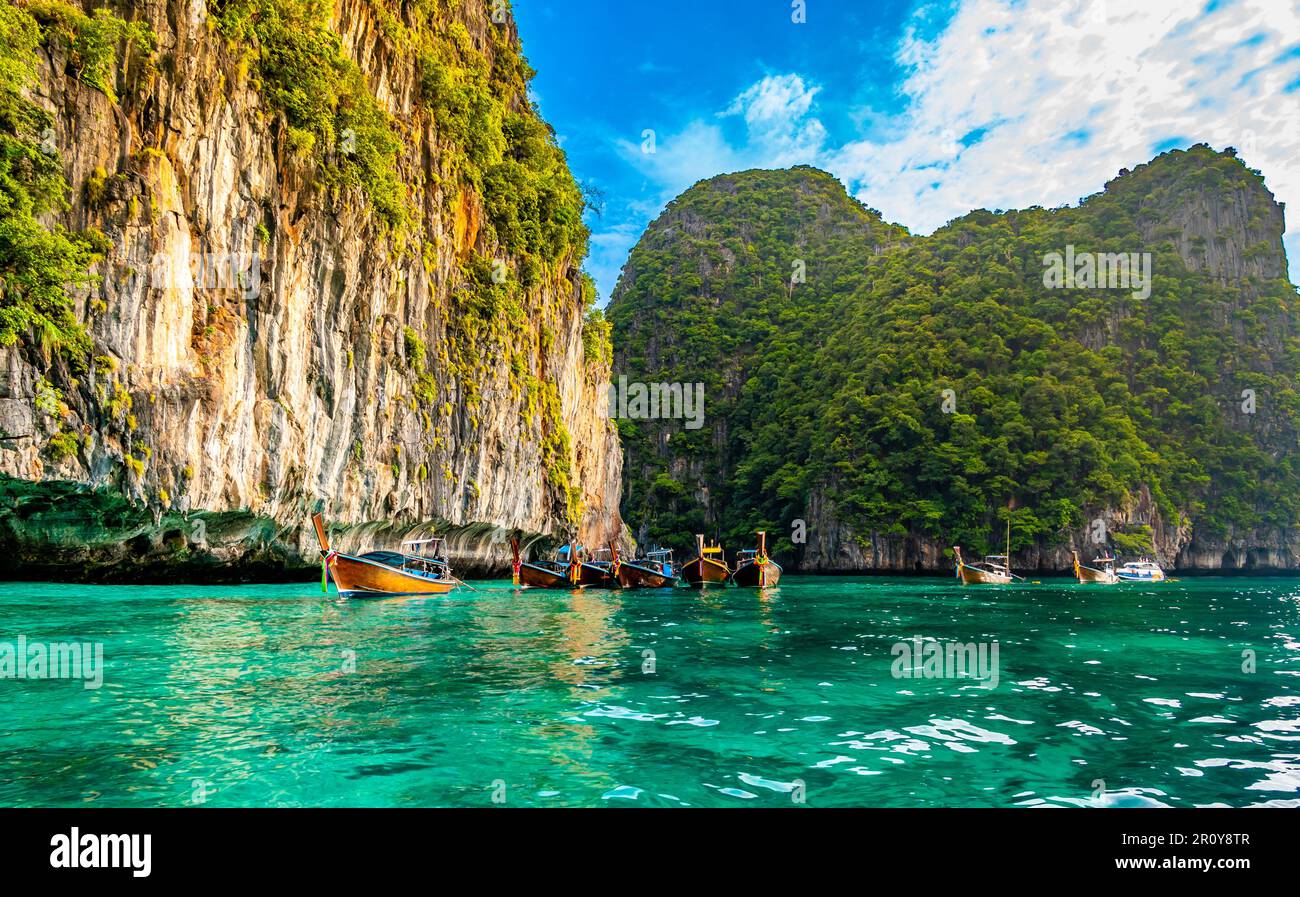 Vue sur les bateaux à longue queue sur l'eau turquoise à l'océan près des îles de Ko Phi Phi, Thaïlande. Concept de vacances exotiques dans le paradis tropical. Roche calcaire Banque D'Images