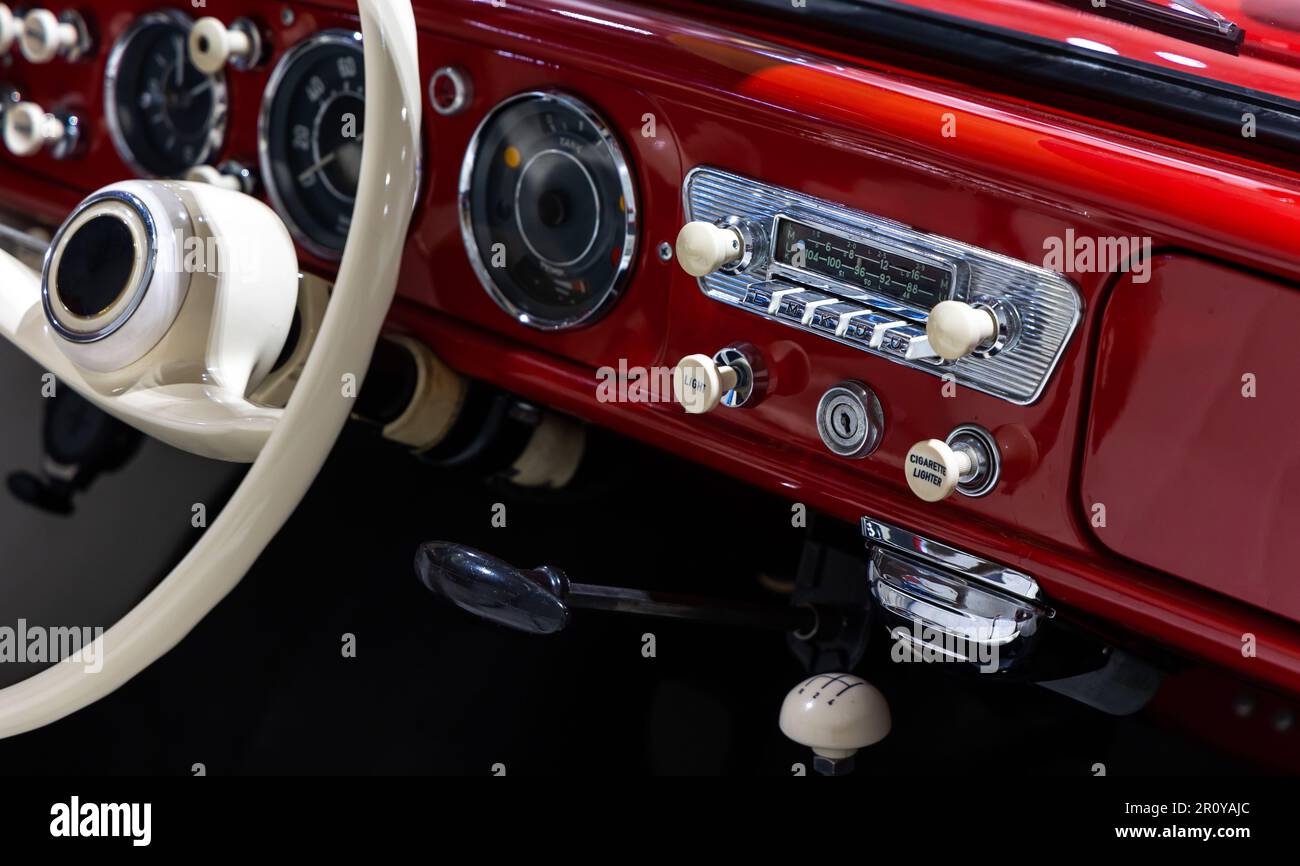 Tableau de bord d'une élégante voiture classique rouge. L'excellente restauration du véhicule et de la jante du volant sont visibles Banque D'Images