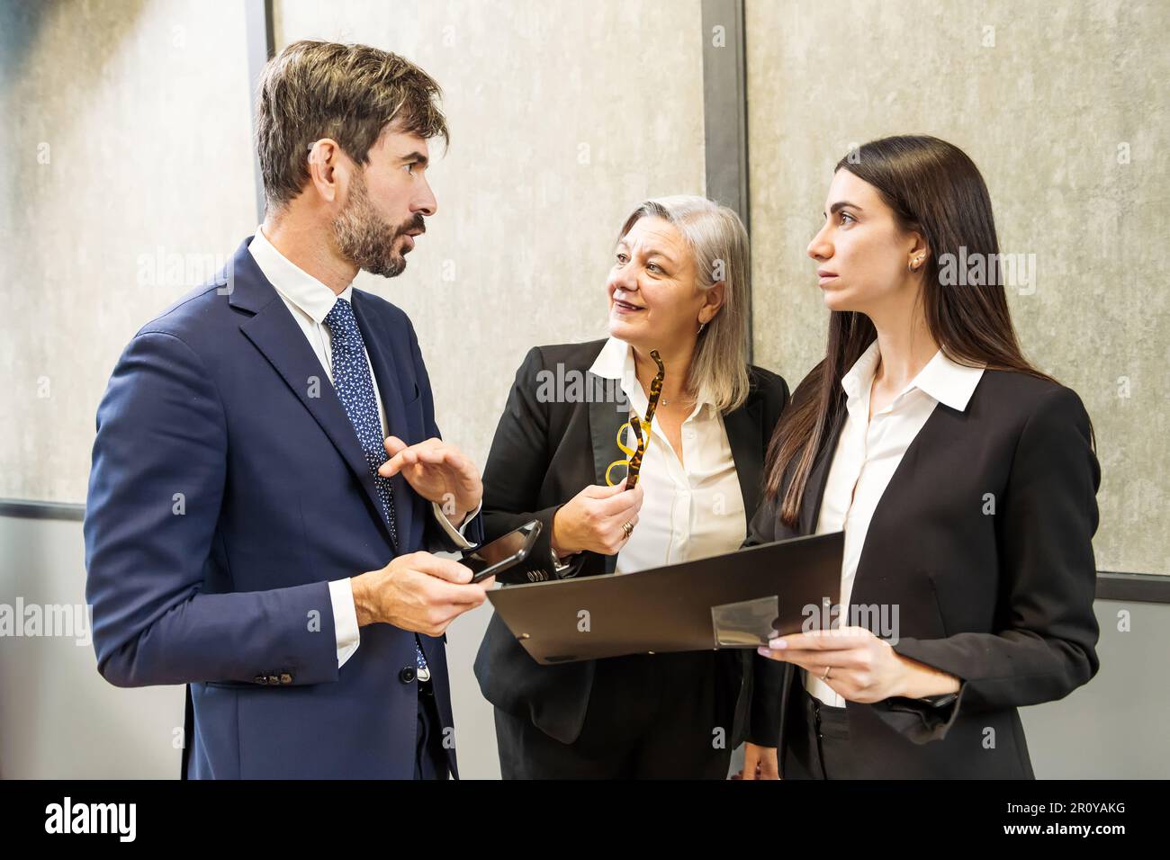 Groupe de collègues vêtres ensemble dans un bureau moderne et parlant de stratégie d'affaires tout en se regardant les uns les autres pendant la réunion Banque D'Images