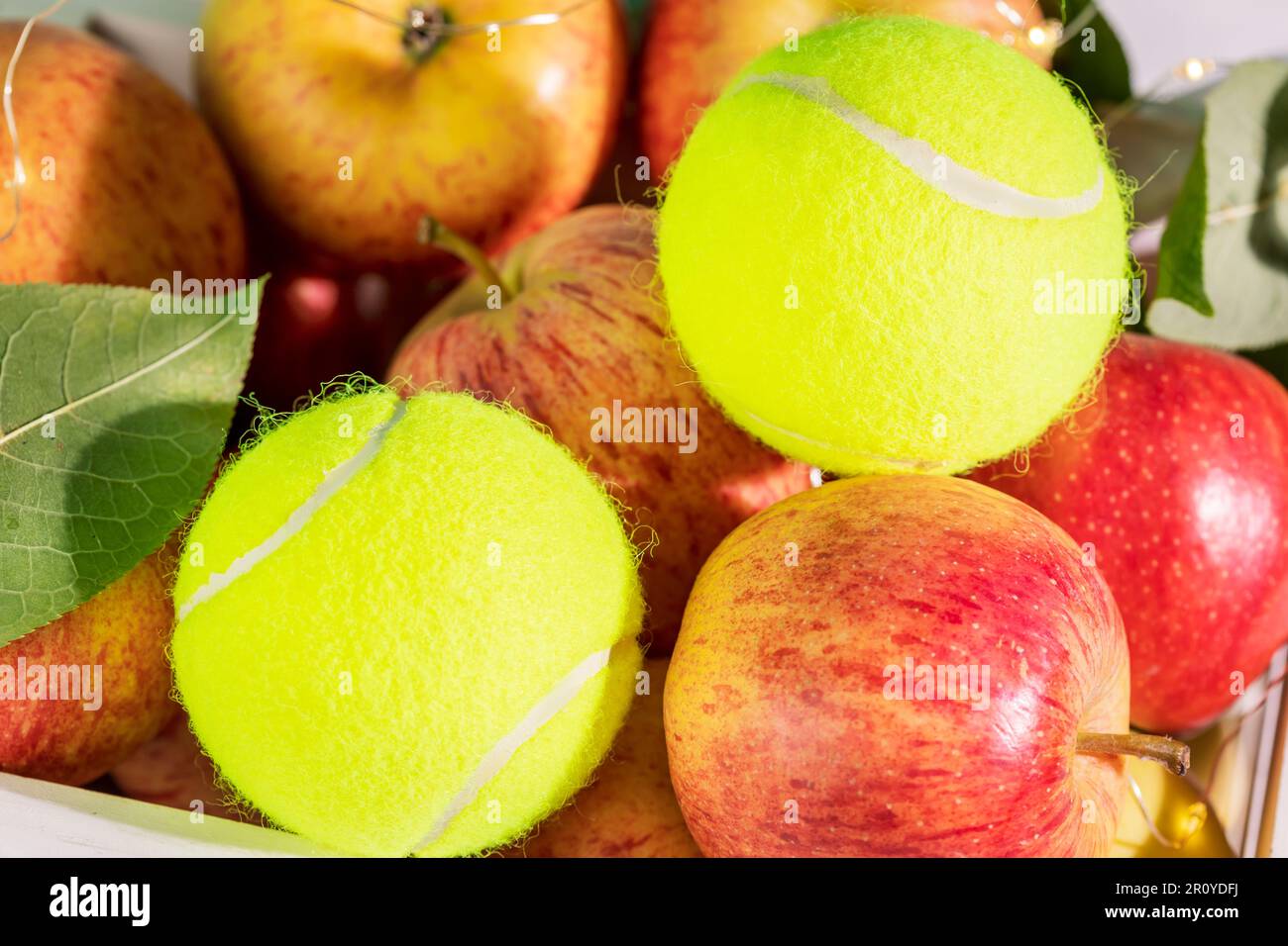Composition de tennis avec balles de tennis jaunes en gros plan et pommes rouges naturelles Banque D'Images